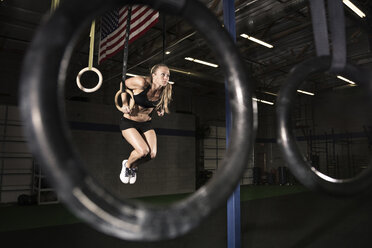 Weibliche Athletin beim Turnen an den Ringen im Fitnessstudio - CAVF28553