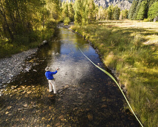 Hoher Blickwinkel auf einen Mann, der ein Band schwenkt, während er im Fluss steht - CAVF28557