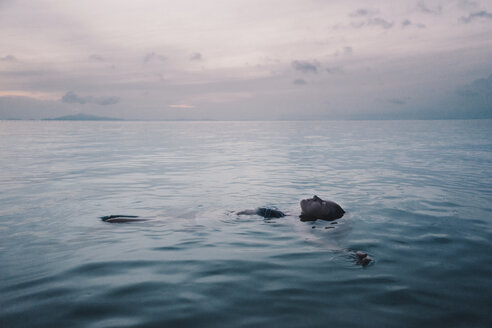 Frau schwimmt auf dem Meer gegen den Himmel bei Sonnenuntergang - CAVF28589