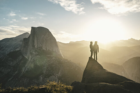 Paar steht auf Klippe gegen Berge an einem sonnigen Tag - CAVF28608