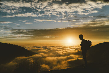 Silhouette male hiker standing on mountain during sunset - CAVF28631