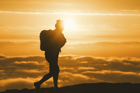 Silhouette einer Wanderin, die bei Sonnenuntergang auf einem Berg wandert - CAVF28632