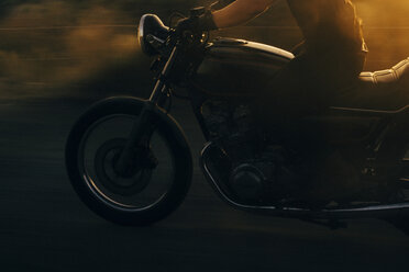 Tiefschnitt eines Mannes beim Motorradfahren auf der Straße bei Sonnenuntergang - CAVF28646