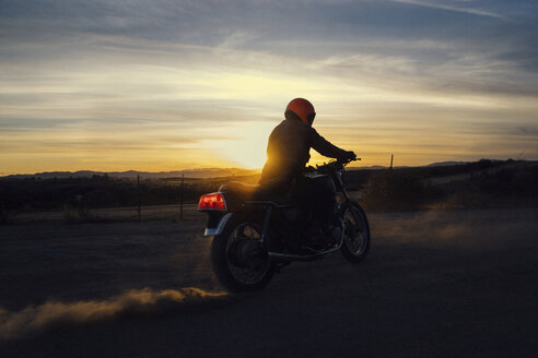 Mann fährt Motorrad auf Feld gegen Himmel bei Sonnenuntergang - CAVF28649