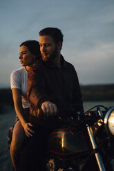 Couple riding motorcycle on field against sky - CAVF28650