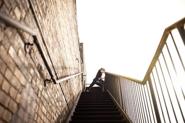 Female athlete exercising on staircase by wall against clear sky - CAVF28674