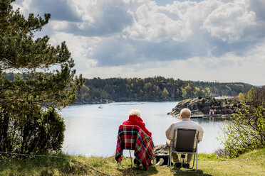 Senior couple sitting on lounge chairs and looking at view - FOLF00977