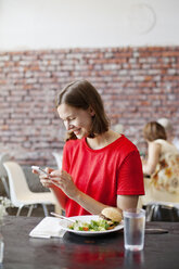 Smiling woman checking smart phone at lunch - FOLF01026