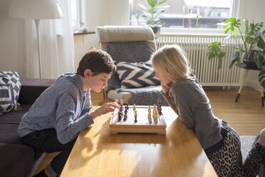 Junge und Mädchen spielen Schach im Wohnzimmer - FOLF01108