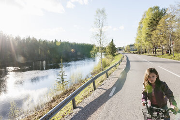 Little girl riding bicycle along road by river - FOLF01159