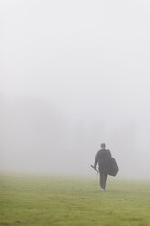Jugendlicher, der im grünen Feld im Nebel spazieren geht - FOLF01161