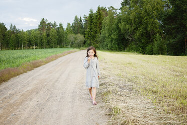 Girl wearing dress walking along dirt road - FOLF01180