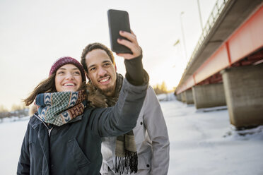 Young couple taking selfie by bridge in winter - FOLF01201