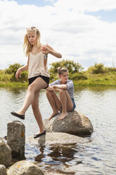 Teenage girls walking and sitting on rocks in water - FOLF01209