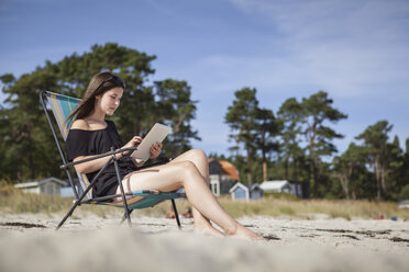 Teenage girl using digital tablet on beach - FOLF01215