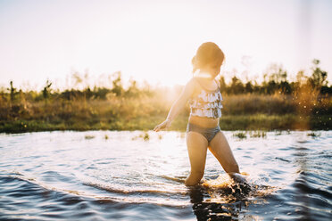 Girl walking in canal against sky during sunset - CAVF28708