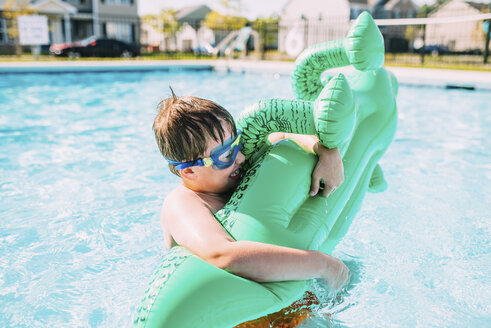 Fröhlicher Junge, der ein Floß im Schwimmbad hält - CAVF28713