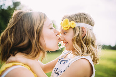 Woman kissing daughter on nose at park - CAVF28718