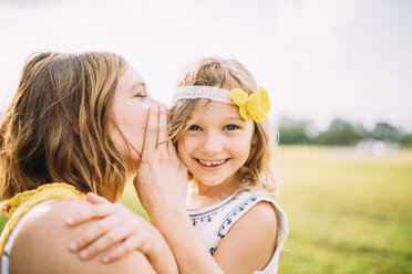 Mother whispering to girl at park - CAVF28719