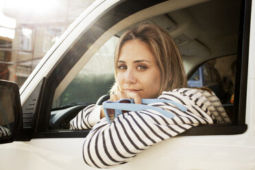 Porträt einer selbstbewussten Frau, die eine Sonnenbrille hält und im Auto sitzt - CAVF28772