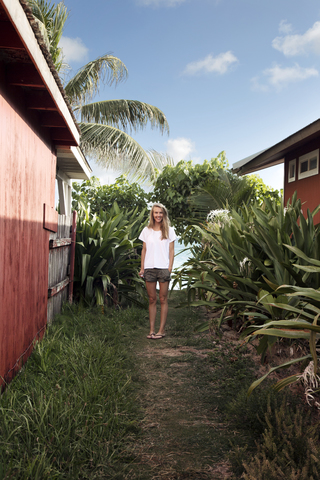 Porträt einer glücklichen Frau, die inmitten von Strandhütten steht, lizenzfreies Stockfoto