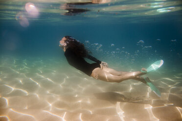 Side view of young woman swimming in sea stock photo