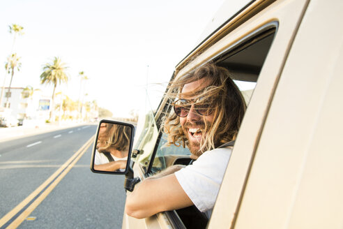 Portrait of cheerful man in mini van on road - CAVF28805