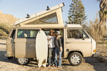 Liebende Frau küsst Mann mit Surfbrett vor Minivan am San Onofre State Beach - CAVF28810