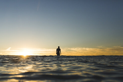 Entfernte Ansicht der weiblichen Surfer auf Meer gegen Himmel während des Sonnenuntergangs - CAVF28816