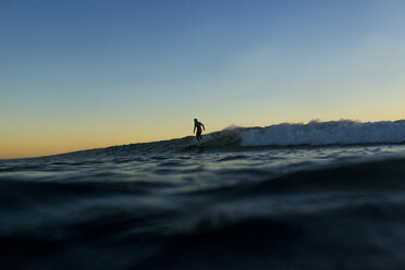 Entfernte Ansicht der Silhouette Mann Surfen auf dem Meer bei Sonnenuntergang - CAVF28817