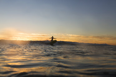 Entfernte Ansicht der Silhouette Frau Surfen auf dem Meer während des Sonnenuntergangs - CAVF28820
