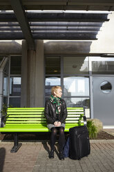 Frau sitzt auf einer Bank am Flughafen - FOLF01301