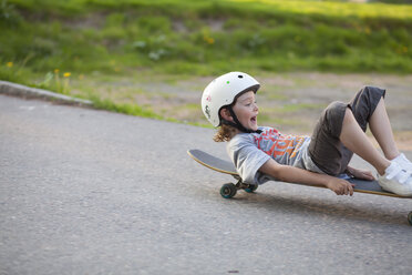 Junge rutscht auf dem Skateboard die Straße hinunter - FOLF01339