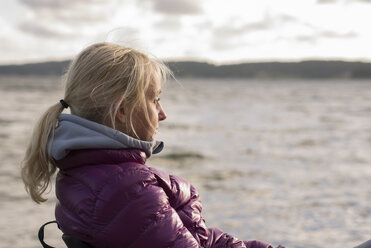 Portrait of blonde mature woman sitting at seaside - FOLF01346