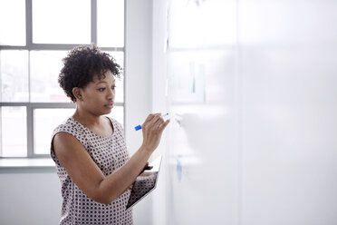 Businesswoman writing on whiteboard in office - CAVF28874