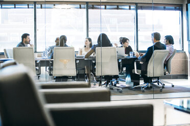 Business people discussing in meeting at board room seen through window - CAVF28916