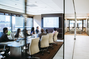 Business people discussing in meeting at conference room seen through doorway - CAVF28931