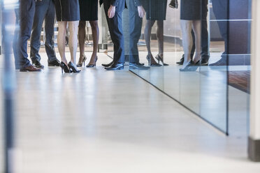 Low section of business people standing in office corridor - CAVF28939