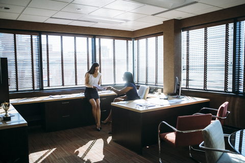 Weibliche Kollegen besprechen Berichte im Büro, lizenzfreies Stockfoto