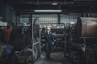 Porträt einer Arbeiterin, die in einer Fabrik vor der Tür steht - CAVF28960