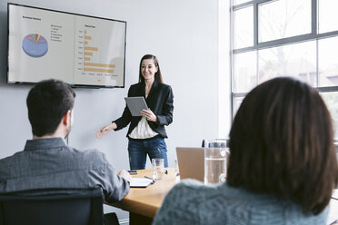 Confident businesswoman giving presentation to colleagues in meeting at board room - CAVF29018