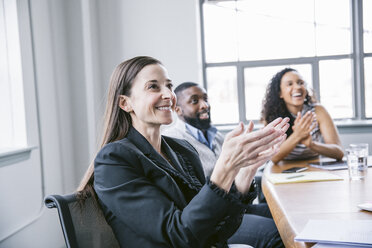 Happy business people applauding in meeting at board room - CAVF29025