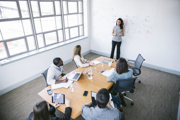 Blick von oben auf eine Geschäftsfrau, die Daten erklärt, während sie an einem Whiteboard im Sitzungssaal steht - CAVF29031