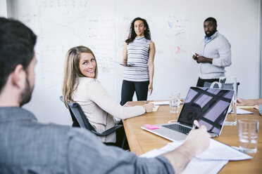 Colleagues looking at businessman in meeting at board room - CAVF29032