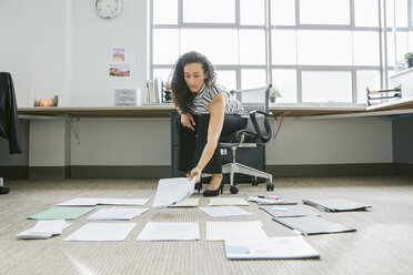 Businesswoman arranging documents on floor in office - CAVF29064