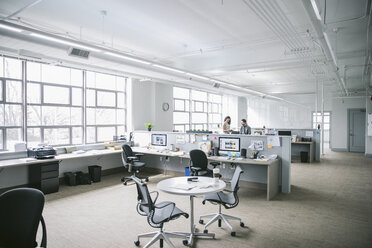 Mid distance view of colleagues discussing paperwork while standing by desk in office - CAVF29095