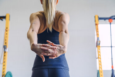 Rückansicht einer Frau, die ihre Hände hinter dem Rücken ausstreckt, während sie im Fitnessstudio trainiert - CAVF29115