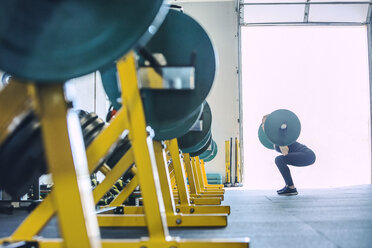 Seitenansicht einer Frau, die eine Langhantel im Fitnessstudio hebt - CAVF29116