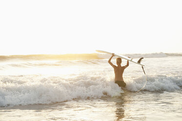 Teenager with surfboard wading in sea at Costa Rica - FOLF01359