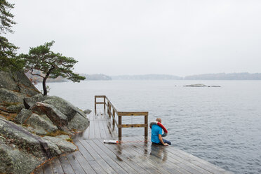 Mann sitzt auf der Seebrücke und schaut auf die Ostsee - FOLF01443